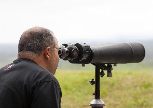 Western tourist looking south Korea with binoculars at the DMZ, North Hwanghae, Panmunjom, North Korea