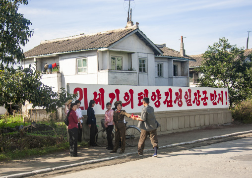 People near propaganda billboards, South Pyongan, Chongsan-ri Cooperative Farm, North Korea
