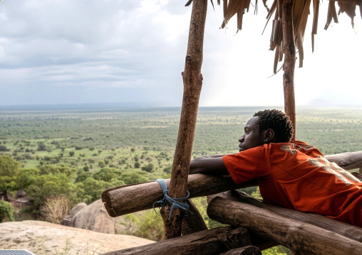 Lotuko tribe man resting on a wood bed, Central Equatoria, Illeu, South Sudan