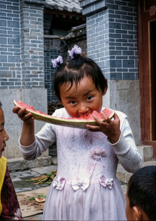 Naxi girl eating watermelon, Lijiang, Yunnan Province, China