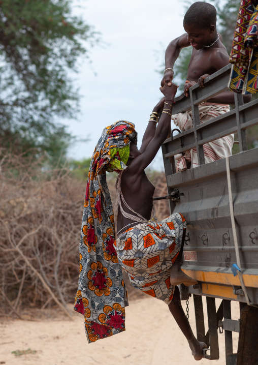 Mucubal tribe people jumping on the back of a truck, Namibe Province, Virei, Angola