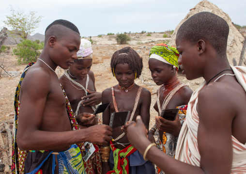 Mucubal tribe people looking at polaroids, Namibe Province, Virei, Angola