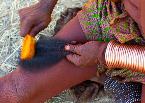 Himba tribe woman combing dreadlocks with hair extensions, Cunene Province, Oncocua, Angola