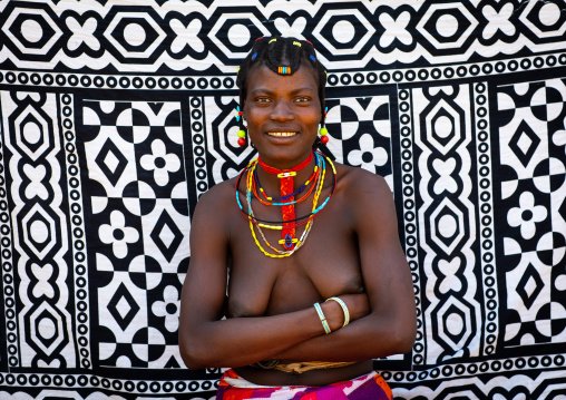 Portrait of a smiling mudimba tribe woman in front of a printed cloth, Cunene Province, Cahama, Angola