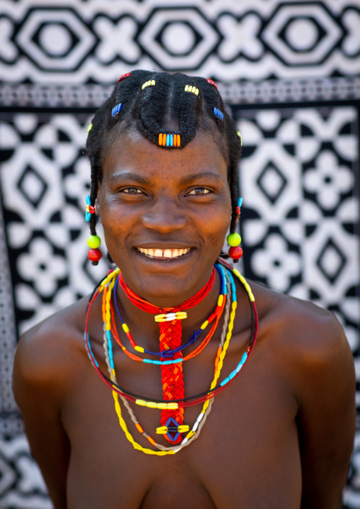 Portrait of a smiling mudimba tribe woman in front of a printed cloth, Cunene Province, Cahama, Angola