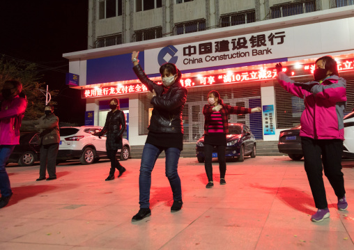Chinese women dancing in the street at night, Qinghai province, Xunhua, China