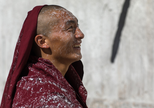 tibetan Monk with white painting on his face while renovating the walls of a temple in Rongwo monastery, Tongren County, Longwu, China