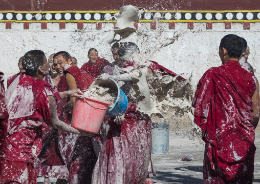 Tibetan monks enjoying a water fight after the yearly renovation of the Rongwo monastery, Tongren County, Longwu, China