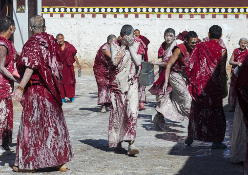 Tibetan monks enjoying a water fight after the yearly renovation of the Rongwo monastery, Tongren County, Longwu, China
