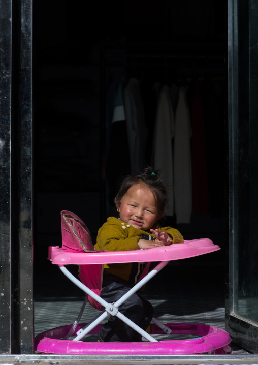 Portrait of a girl sit in her baby walker, Qinghai province, Tsekhog, China