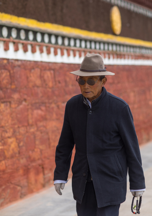 A tibetan pilgrim fingers his prayer beads around a temple, Gansu province, Hezuo, China