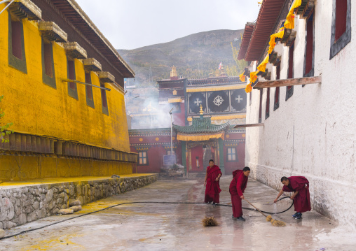 Buddhist monks in red robes are cleaning Rongwo monastery, Tongren County, Longwu, China