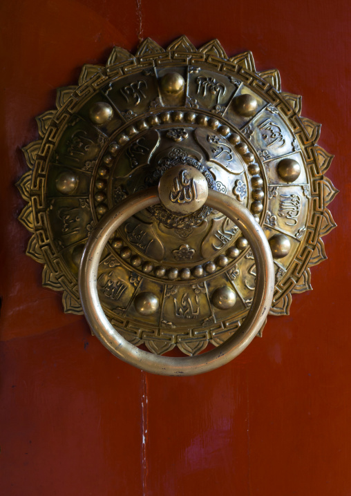 Ornate knocker with arabic scripts on traditional door in Yu Baba Gongbei islamic shrine complex, Gansu province, Linxia, China