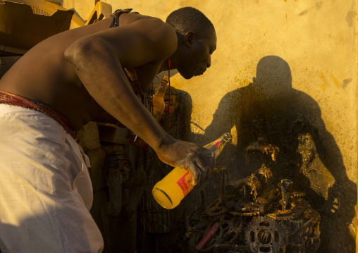 Benin, West Africa, Bonhicon, kagbanon bebe voodoo priest drinking orange juice and spitting it on ogun god altar made with pedaliers biking
