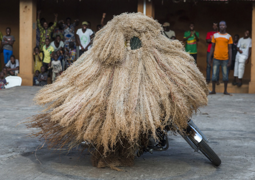 Benin, West Africa, Porto-Novo, zangbeto guardian of the night spirit riding motorcycle in the royal palace