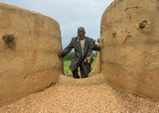 Benin, West Africa, Boukoumbé, man climbing a ladder in a traditional tata somba house
