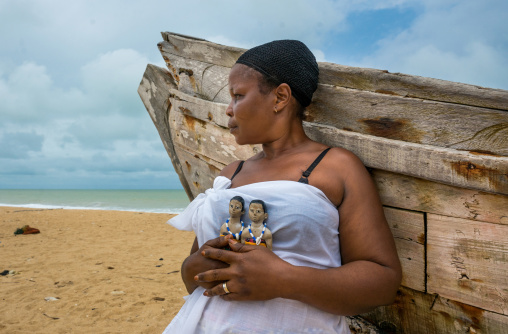 Benin, West Africa, Ouidah, mrs kpsouayo carrying the carved wooden figures made to house the soul of her dead twins