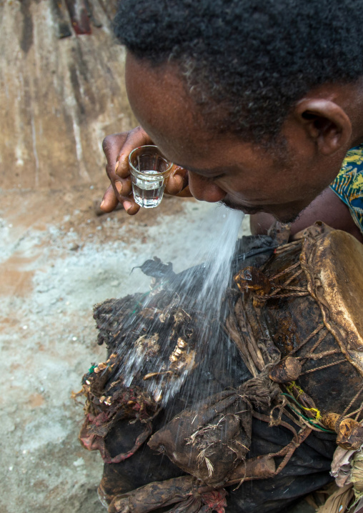 Benin, West Africa, Bopa, drummer spitting alcohol on a drum to wake up its spirit before a voodoo ceremony