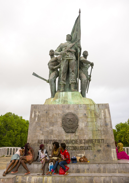 Benin, West Africa, Cotonou, group of girls sitting in front of 1977 martyrs monument made by north korean artists