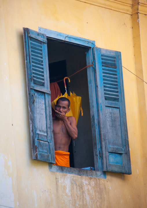 Cambodian monk standing at the window in a monastery, Battambang province, Battambang, Cambodia