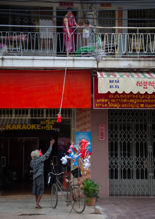 Cambodian mother buying a toy from her balcony, Phnom Penh province, Phnom Penh, Cambodia
