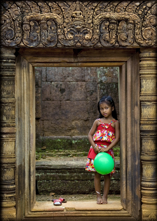 Cambodian little girl with a green balloon in Banteay Srei temple gate, Siem Reap Province, Angkor, Cambodia