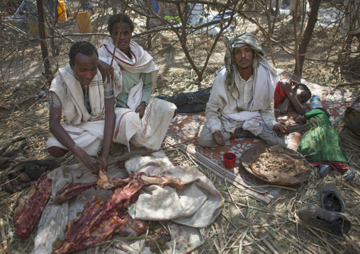 Four Karrayyu Tribe Men Resting And Cutting Meat For The Gadaaa Ceremony, Metahara, Ethiopia