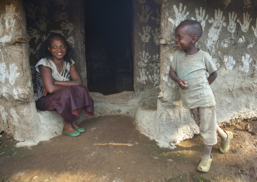 Woman And Her Son In Front Of Their Traditional House Decorated With Handprints To Bring Luck, Tepi, Ethiopia