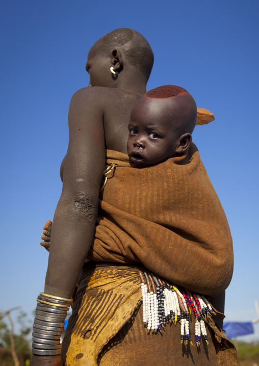 Portrait Of A Bodi Tribe Mother Carrying Her Baby, Hana Mursi, Omo Valley, Ethiopia