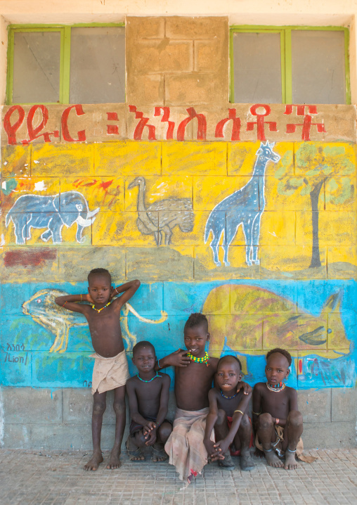 Hamer tribe children in a school in front of a painted wall with wild animals, Omo valley, Turmi, Ethiopia