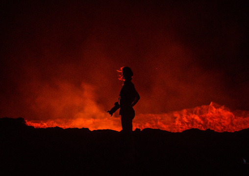 Tourist in front of the living lava lake in the crater of erta ale volcano, Afar region, Erta ale, Ethiopia