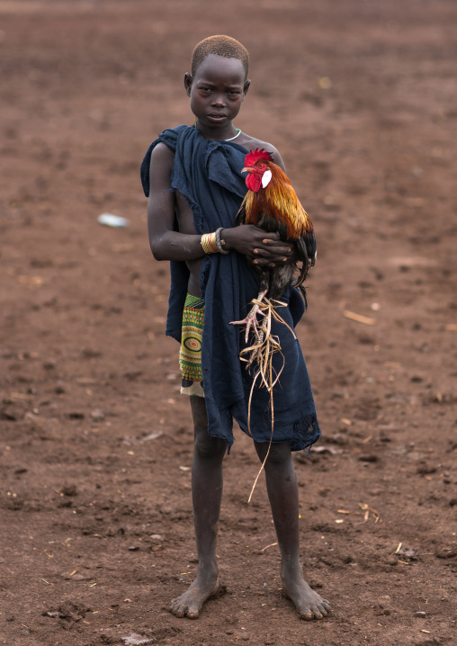 Bodi tribe boy with a rooster going to market, Omo valley, Hana mursi, Ethiopia