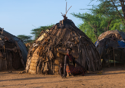 Dassanech tribe woman in front of her house where stays her daughter before dimi ceremony circumcision, Omo valley, Omorate, Ethiopia