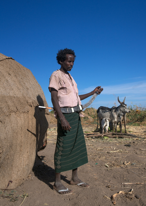 Afar tribe man with his guile knife in front of his hut, Afar region, Afambo, Ethiopia