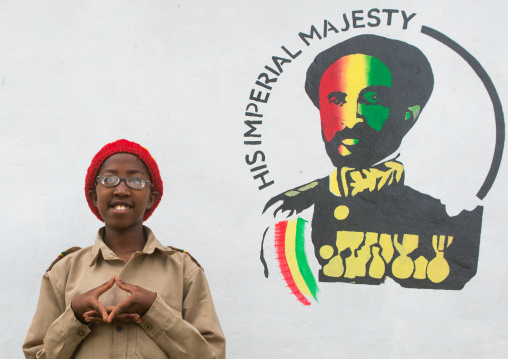 Rastafari girl called kizzy in front of a haile selassie portrait painting, Oromo, Shashamane, Ethiopia