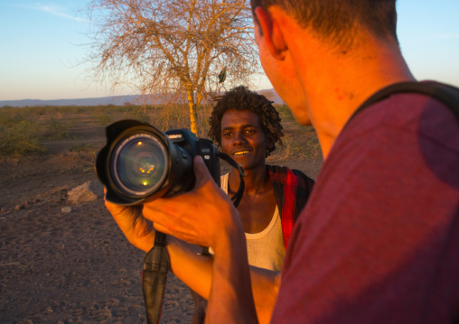 European tourist showing the screen of his camera to an afar tribe man, Afar region, Afambo, Ethiopia