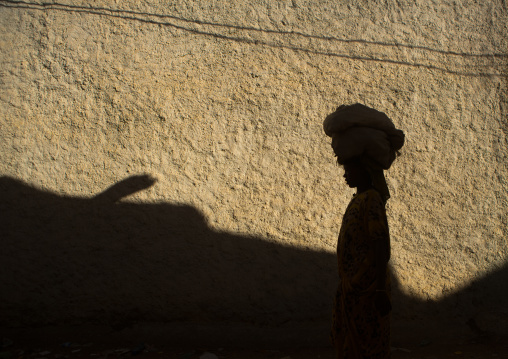 Shadow of a woman carrying stuff on her head on a wall of the old city, Harari region, Harar, Ethiopia