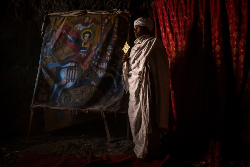 Ethiopian orthodox priest holding a cross inside a rock church, Amhara region, Lalibela, Ethiopia