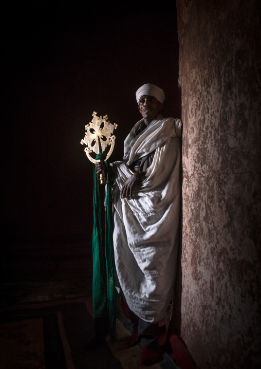 Ethiopian orthodox priest holding a cross inside a rock church, Amhara region, Lalibela, Ethiopia