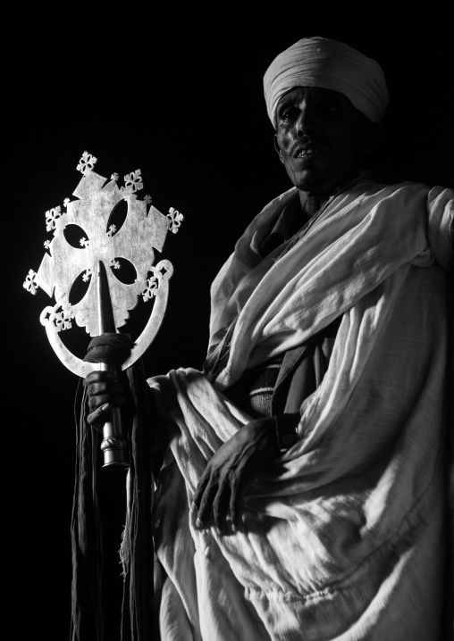 Ethiopian orthodox priest holding a cross inside a rock church, Amhara region, Lalibela, Ethiopia