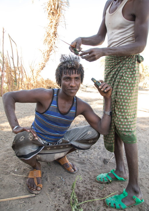 Afar man having a traditional hairstyle with a stick to make curly hair, Afar region, Afambo, Ethiopia