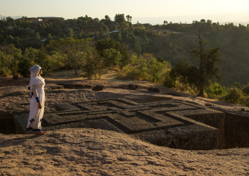 Ethiopian woman standing in front of the monolithic rock-cut church of church of st. George, Amhara region, Lalibela, Ethiopia