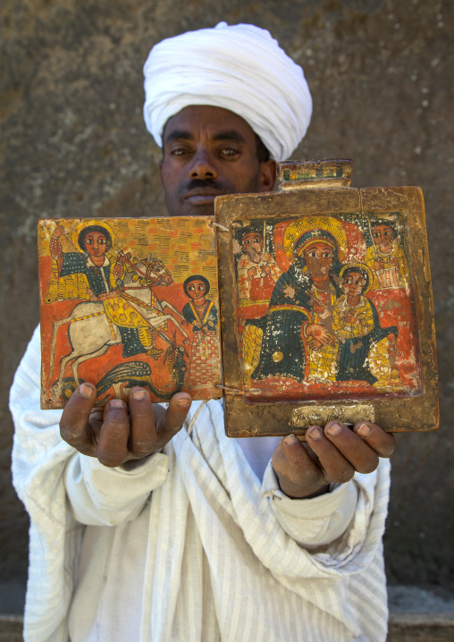 Priest of the ethiopian orthodox church in Asheten mariam rock hewn church holds ancient illuminated icons, Amhara region, Lalibela, Ethiopia