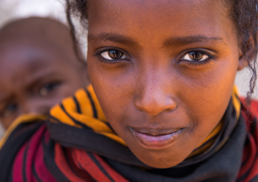 Portrait of a Borana tribe girl carrying her brother on her back, Oromia, Yabelo, Ethiopia