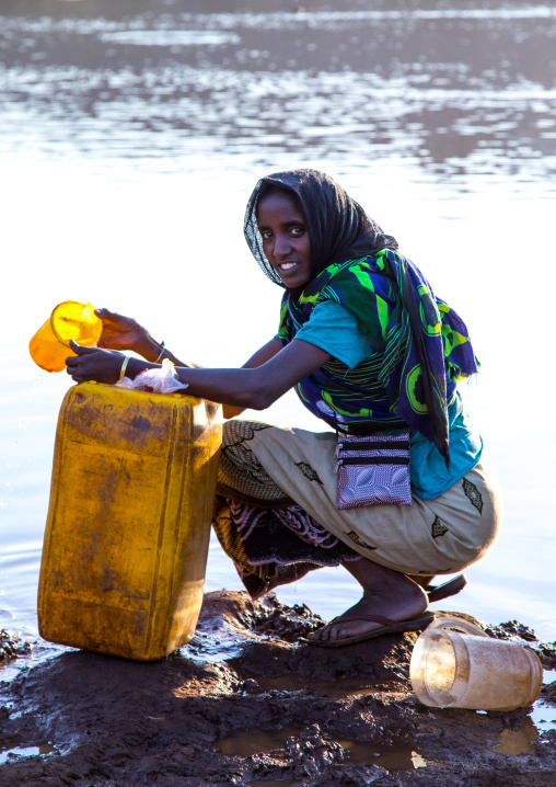 Borana tribe woman filling jerricans in a water reservoir used for animals, Oromia, Yabelo, Ethiopia