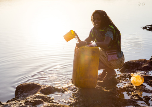 Borana tribe woman filling jerricans in a water reservoir used for animals, Oromia, Yabelo, Ethiopia