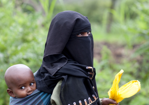 Veiled muslim woman carrying her baby on her back, Ethiopia