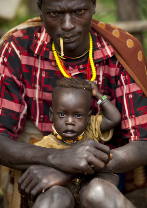 Menit man with his child sitting on his knees, Tum market, Omo valley, Ethiopia