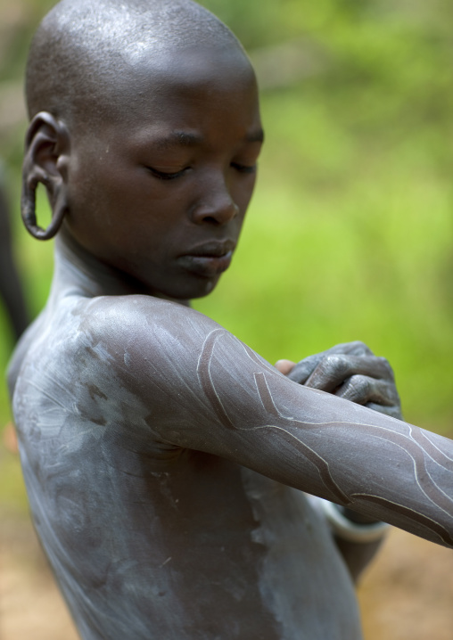 Clay body paintings on Suri warriors before donga stick fighting, Turgit village, Omo valley, Ethiopia