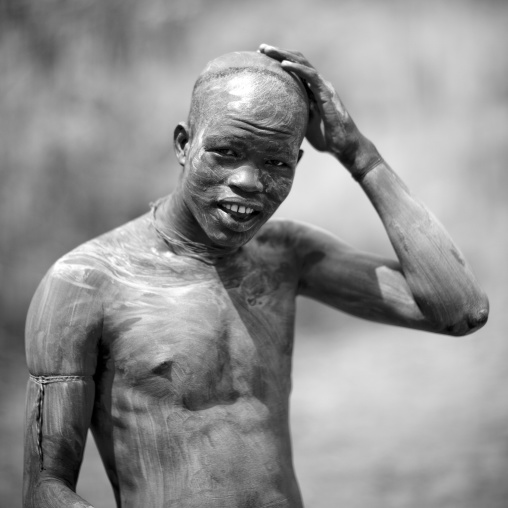 Clay body paintings on Suri warriors before donga stick fighting, Turgit village, Omo valley, Ethiopia